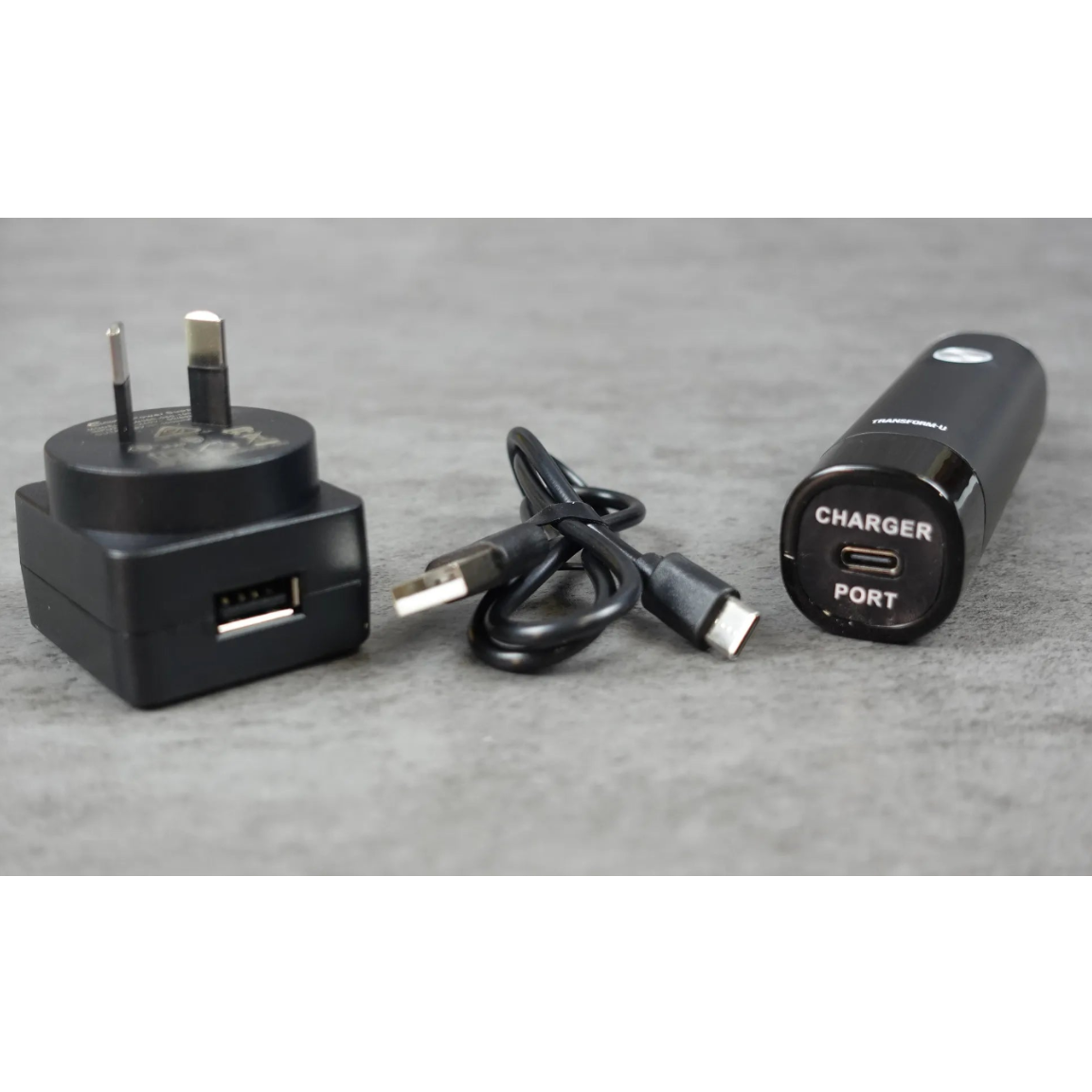 Black nose and ear trimmer charging port, USB-C, cable, and portable charger on a gray surface