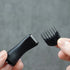 sideburn trimmer and comb held by hands against a gray background