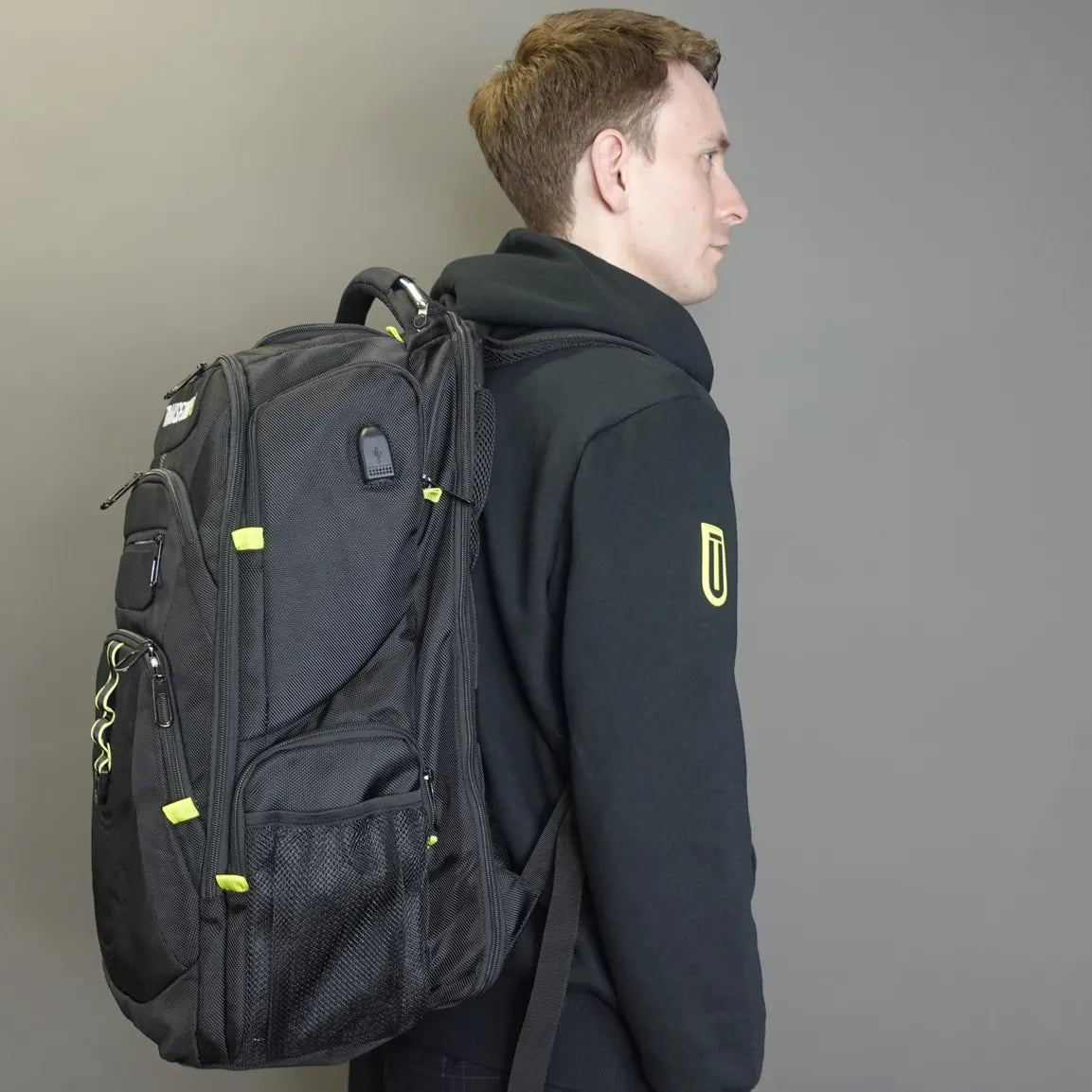 Person wearing a black backpack with a gray background