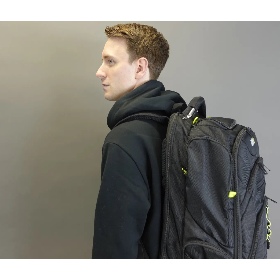 Man wearing a black backpack against a plain background