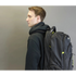 Man wearing a black backpack against a plain background