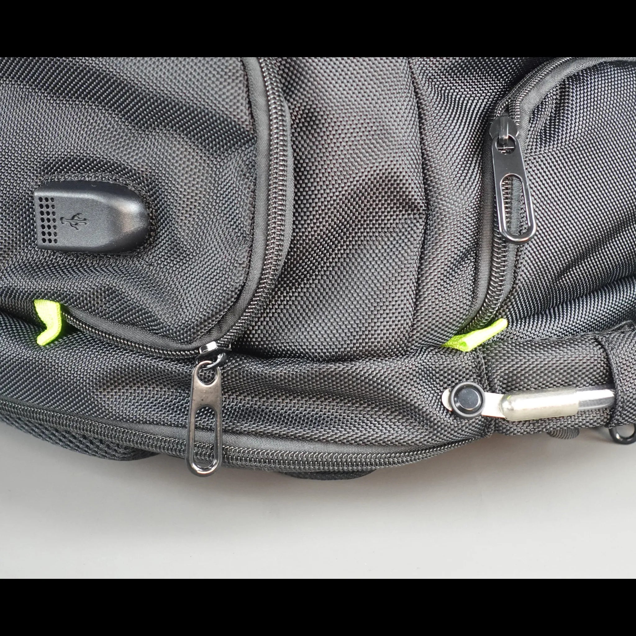 Gray backpack with multiple zippers on a light gray background