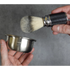 Shaving brush and bowl held by hands against a gray background