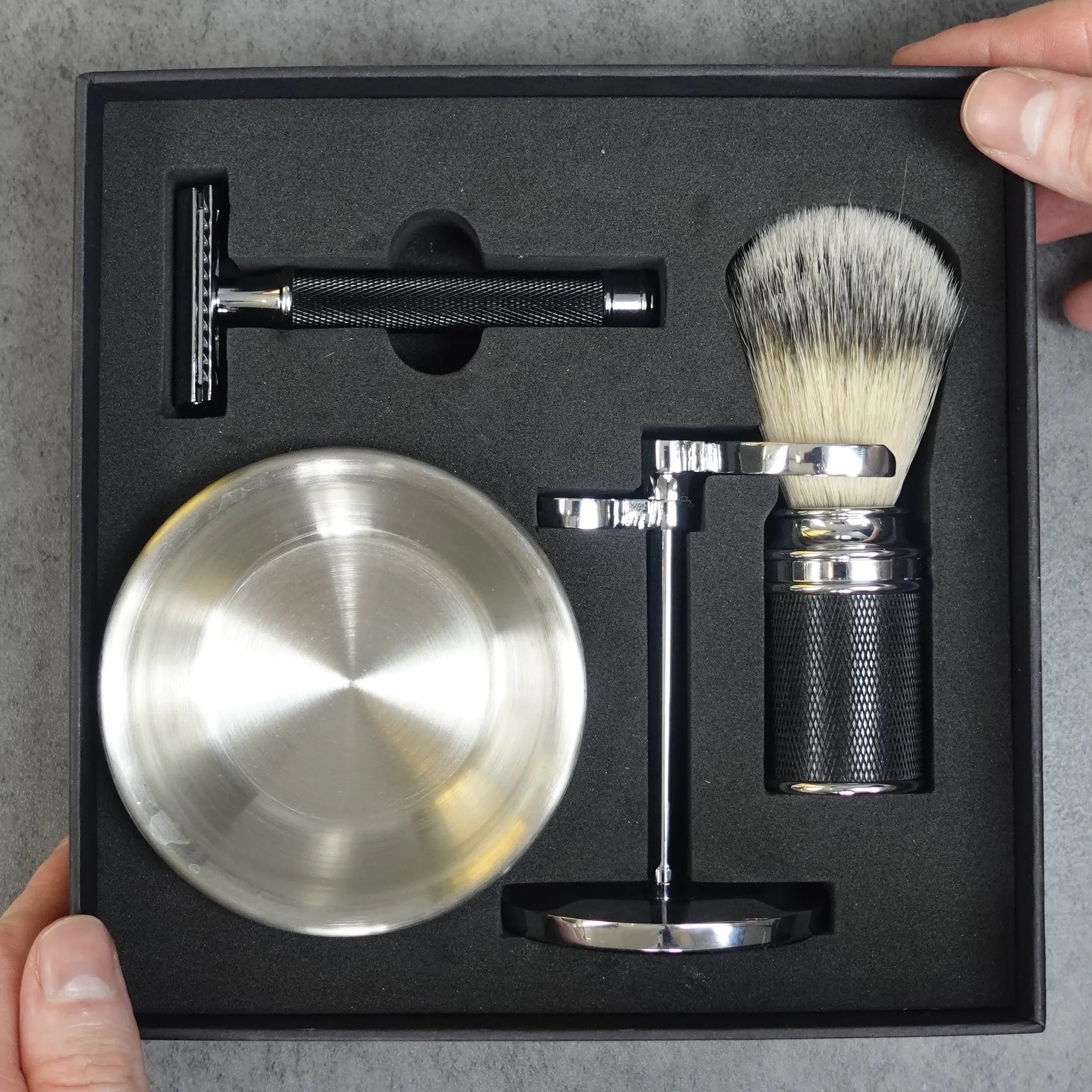Shaving set with razor, bowl, and brush in a black box on a gray background