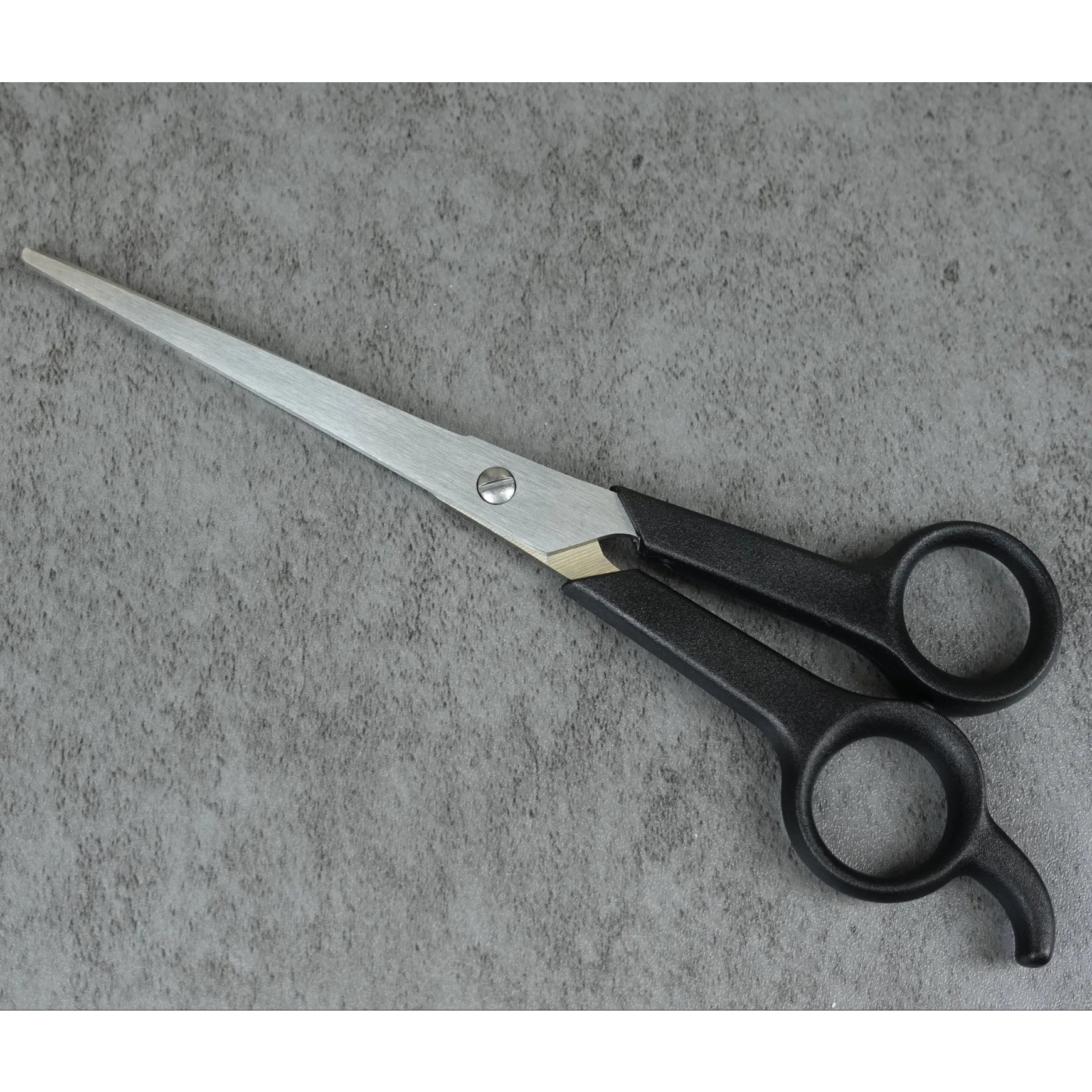 Pair of scissors on a gray concrete surface