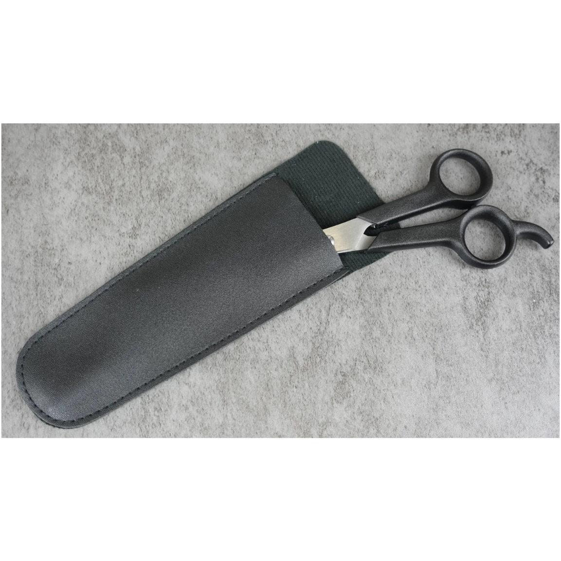 Black scissors in a black sheath on a gray concrete surface