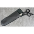Black scissors in a black sheath on a gray concrete surface