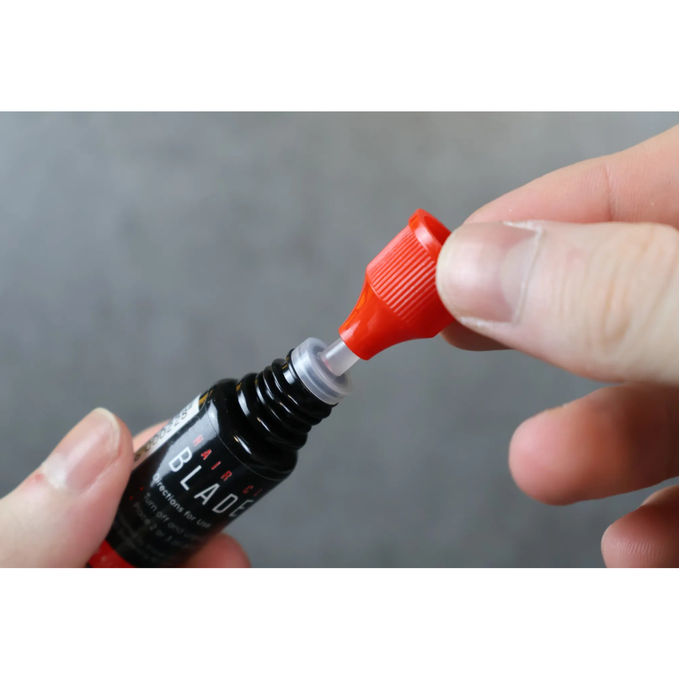 Person using a black blade oil bottle with a close-up of the nozzle.