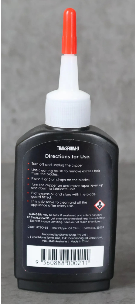 Bottle of back of blade oil bottle with a red cap on a gray background