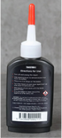 Bottle of back of blade oil bottle with a red cap on a gray background