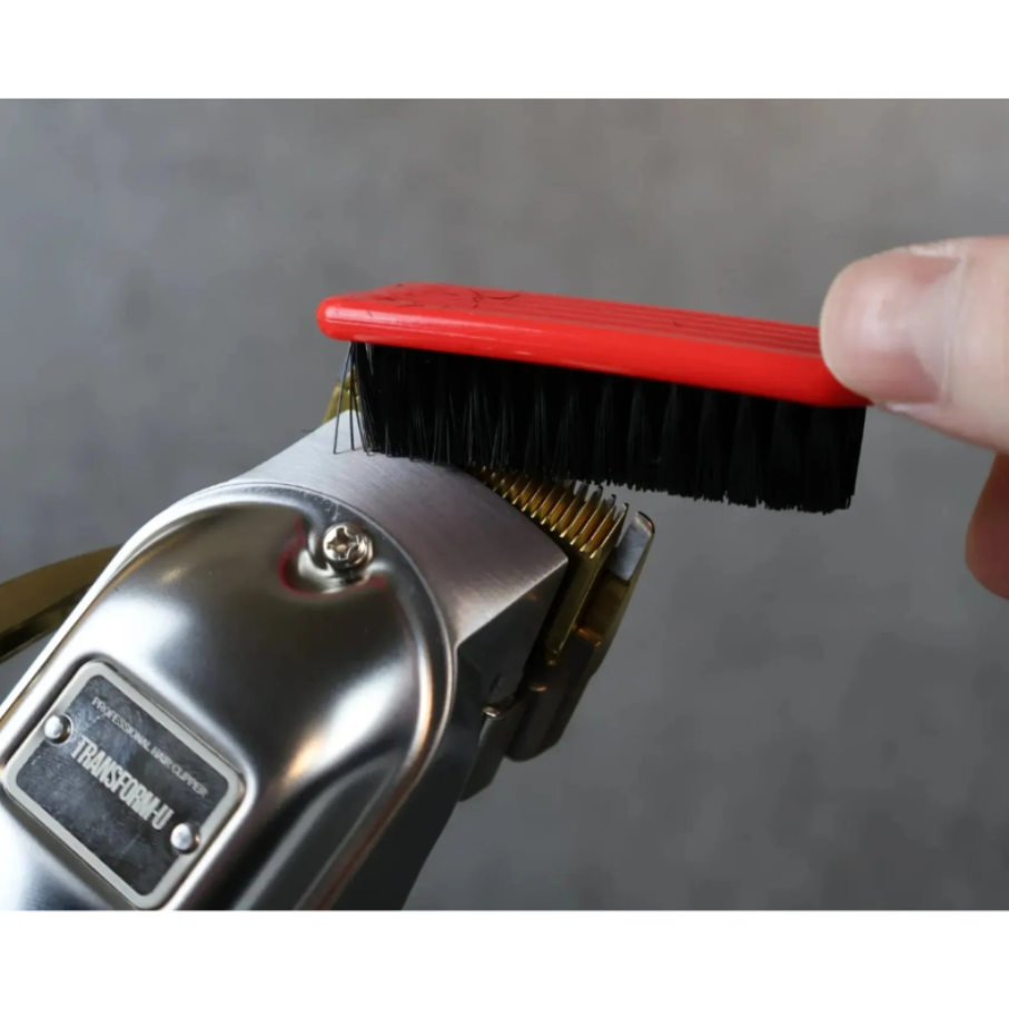 Person using a brush to clean a TRANSFORM-U clipper against a gray background