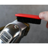 Person using a brush to clean a TRANSFORM-U clipper against a gray background