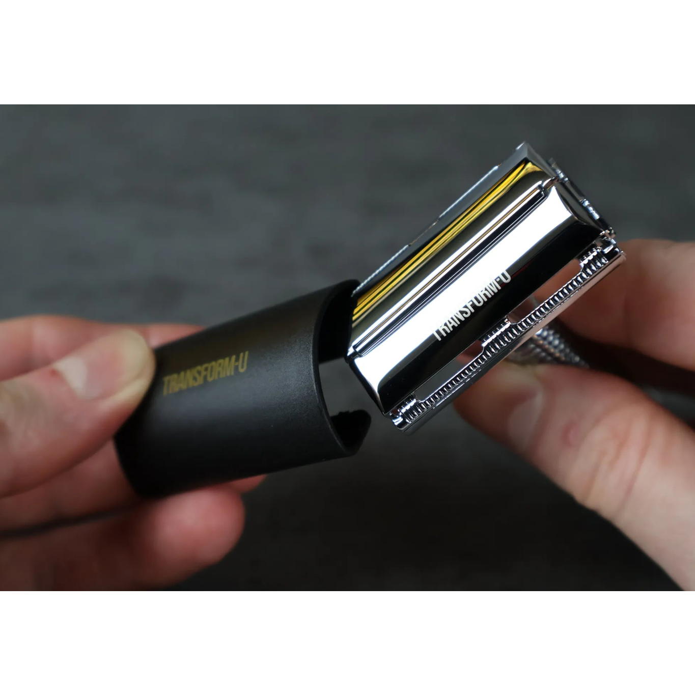Close-up of a person holding a safety razor with a protective cover on a dark background