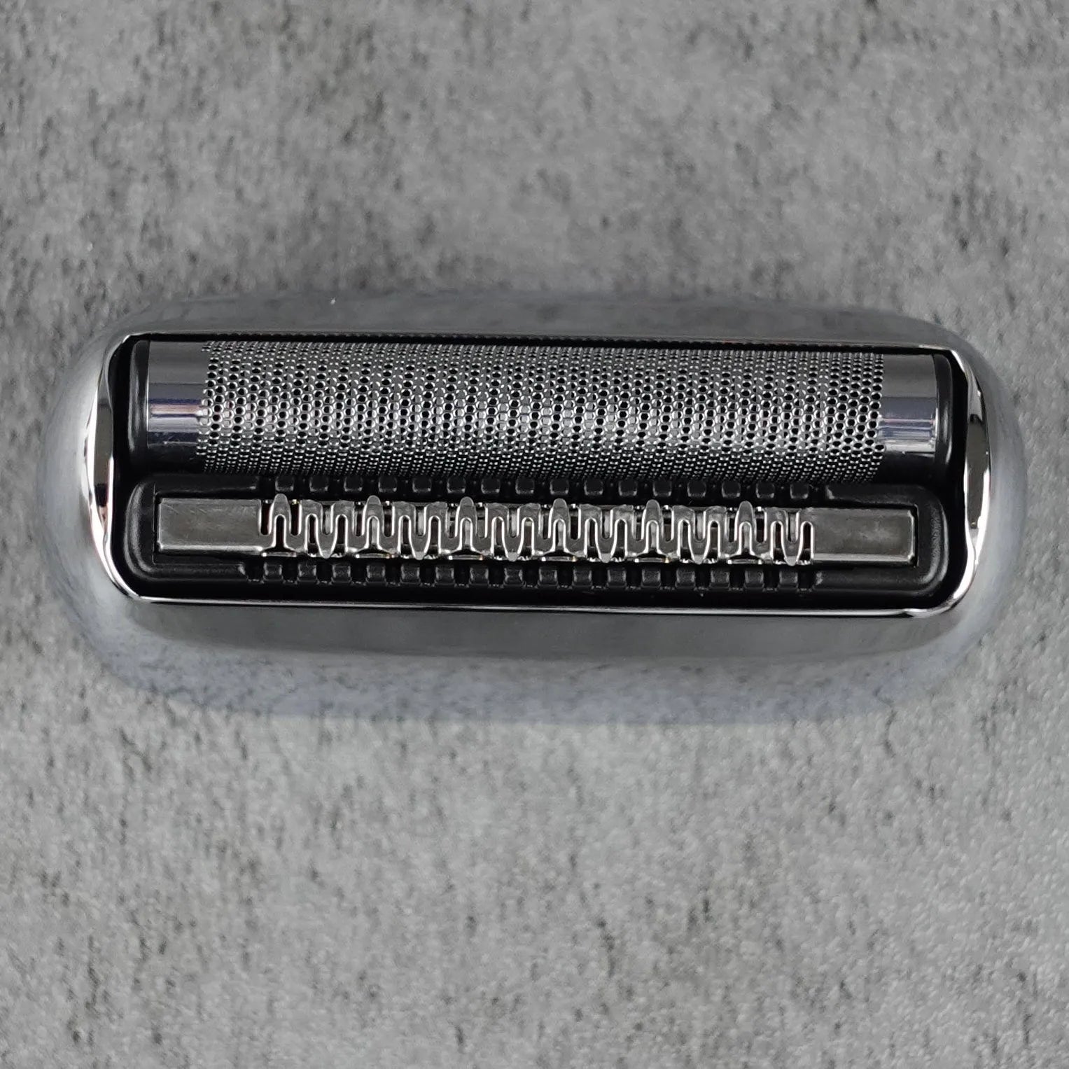 Metallic shaver head on a gray textured background