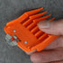 Orange hair clipper guide comb held by a hand on a gray background