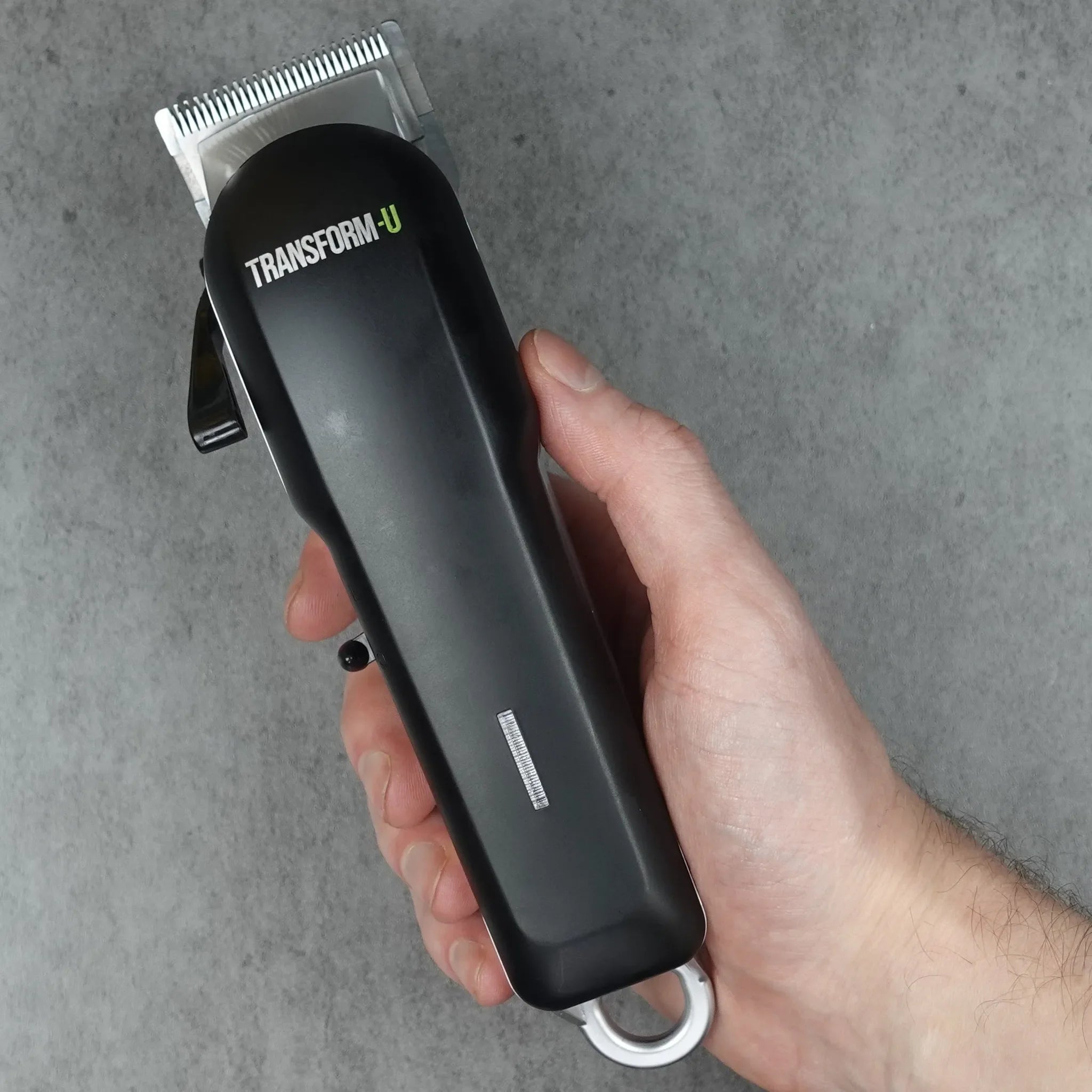 Hand holding a black hair clipper with a gray background