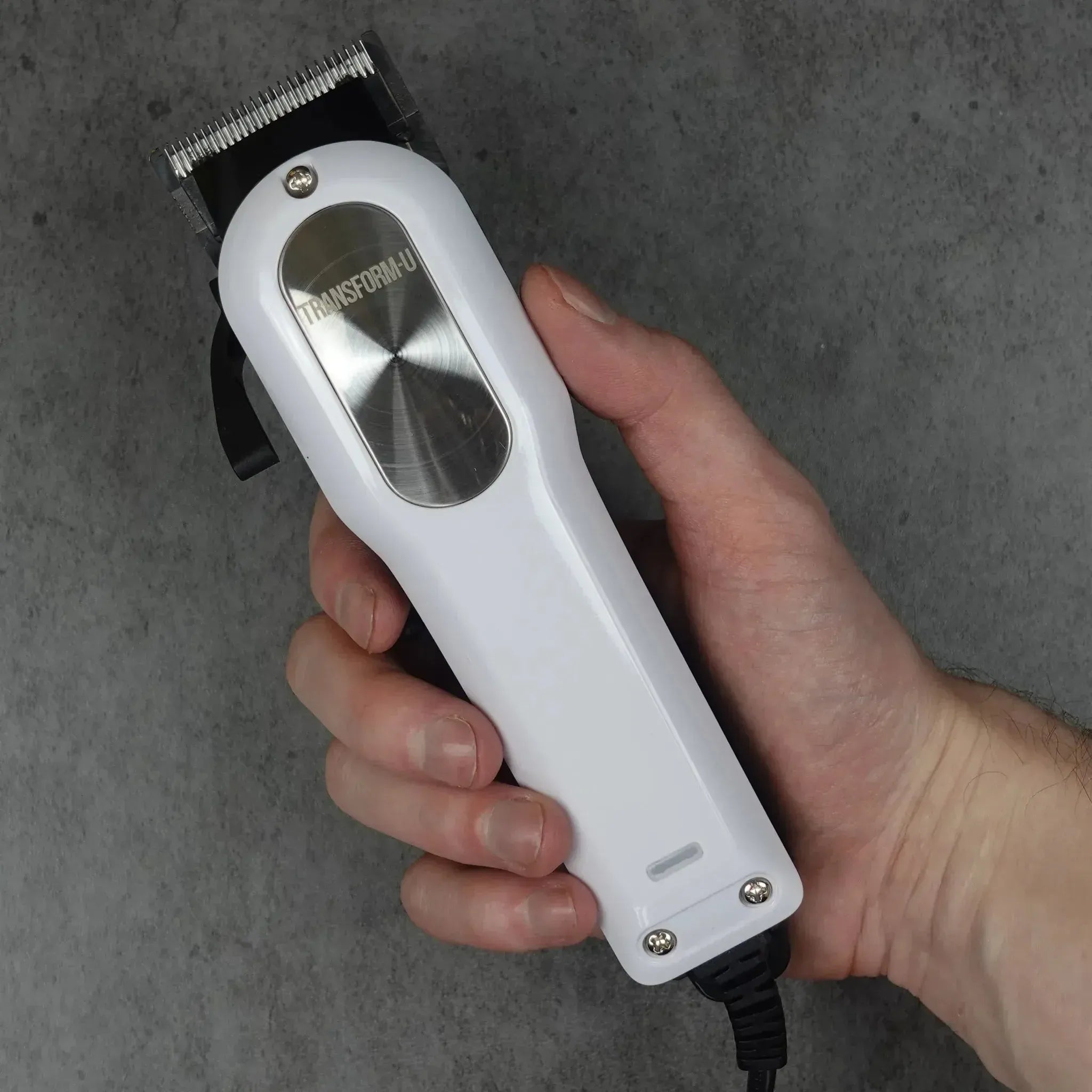Hand holding a white hair clipper against a gray background