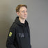 Man wearing a black hoodie with a logo on a gray background