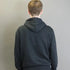 Person wearing a black hoodie from behind against a plain background