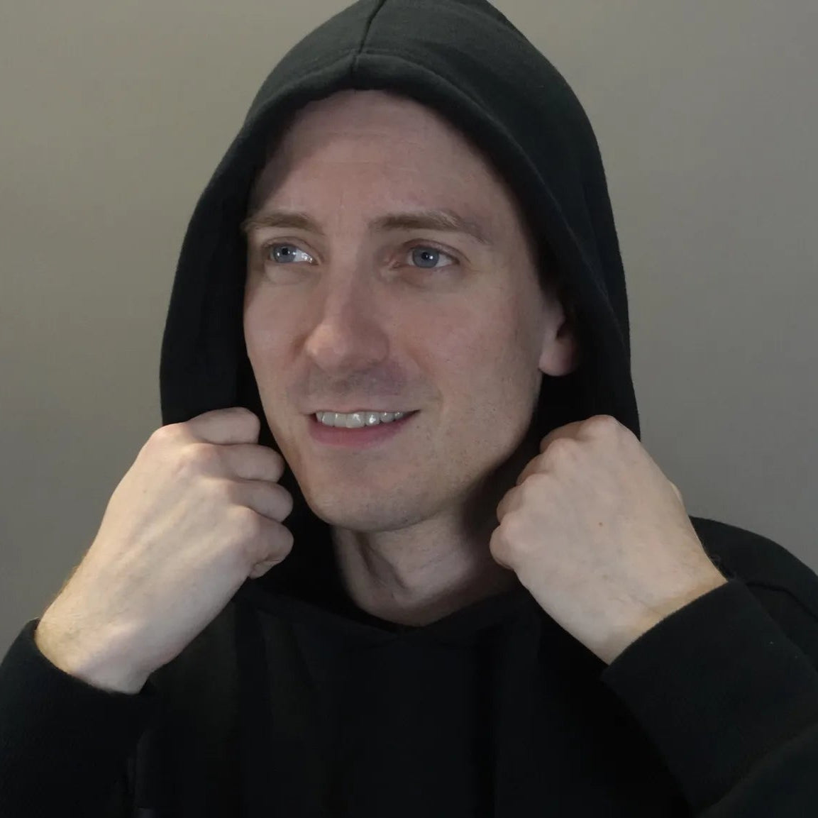 Person wearing a black hoodie against a plain background