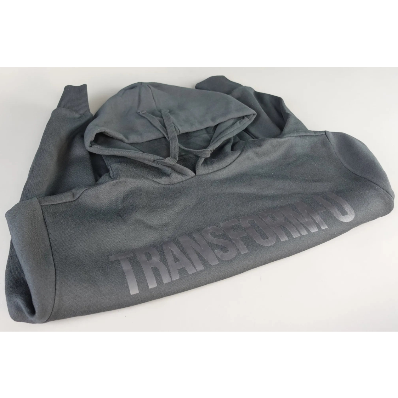 Folded gray hoodie with 'Transform-U' branding on a white background