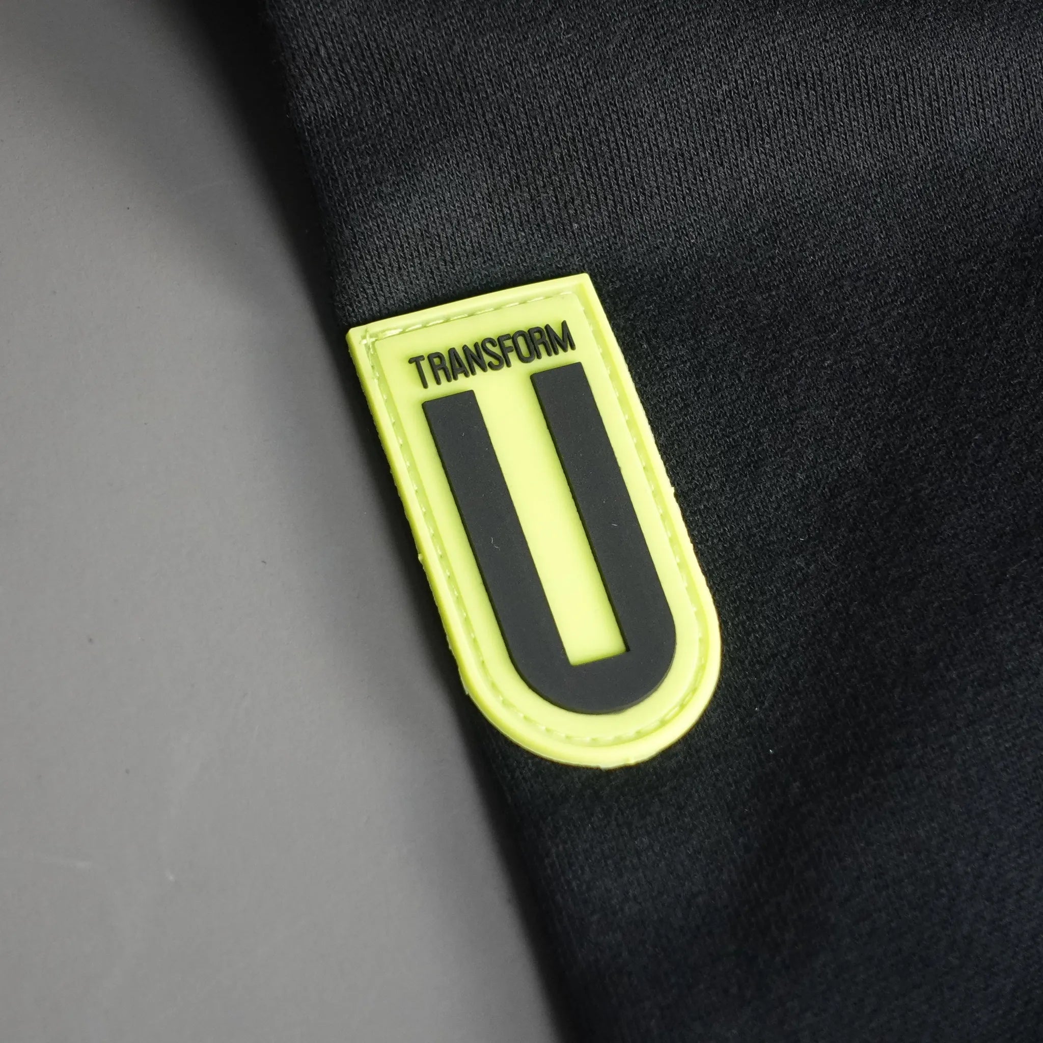Close-up of a black fabric with a yellow logo on a gray background