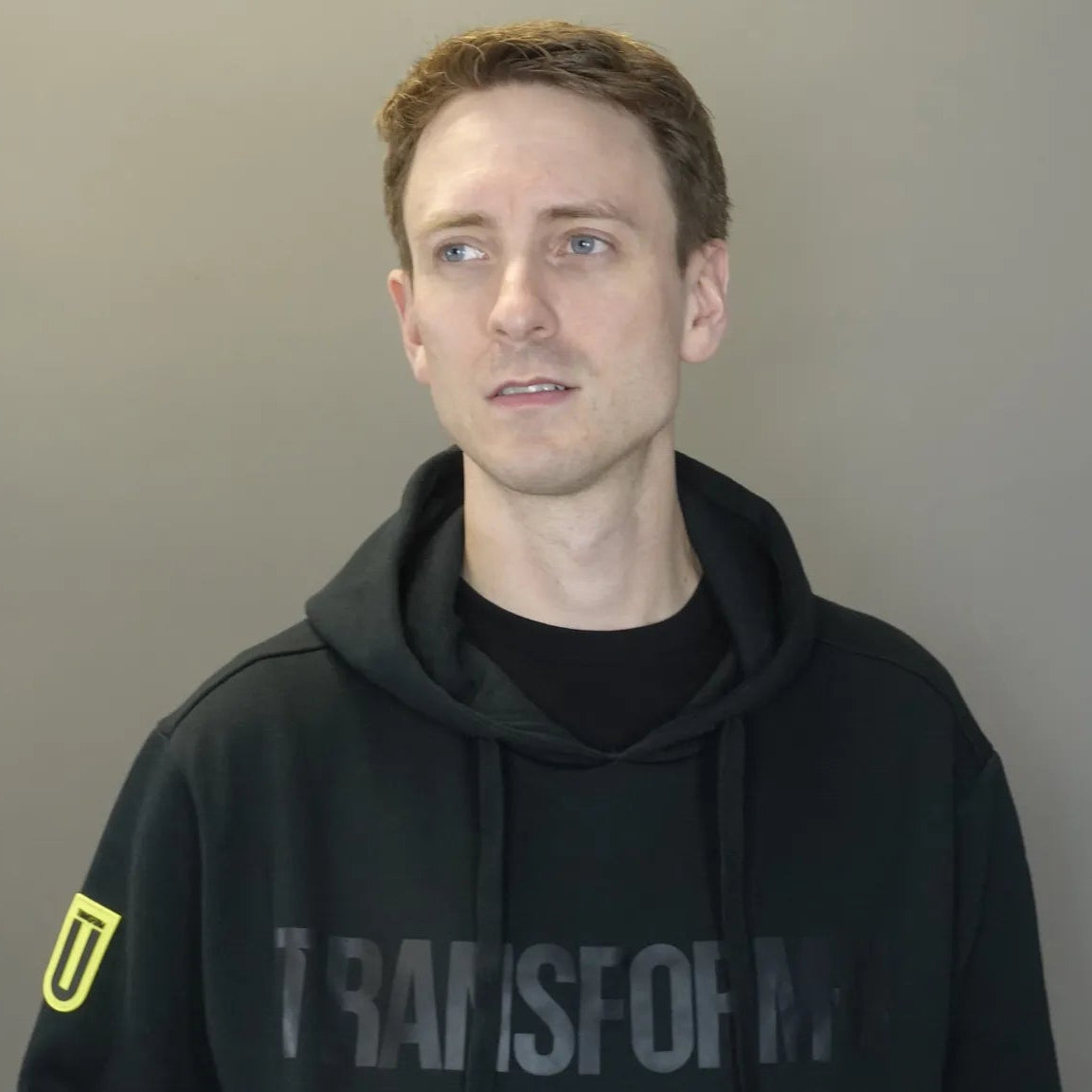 Person wearing a black hoodie with 'Transform-U' text against a plain background
