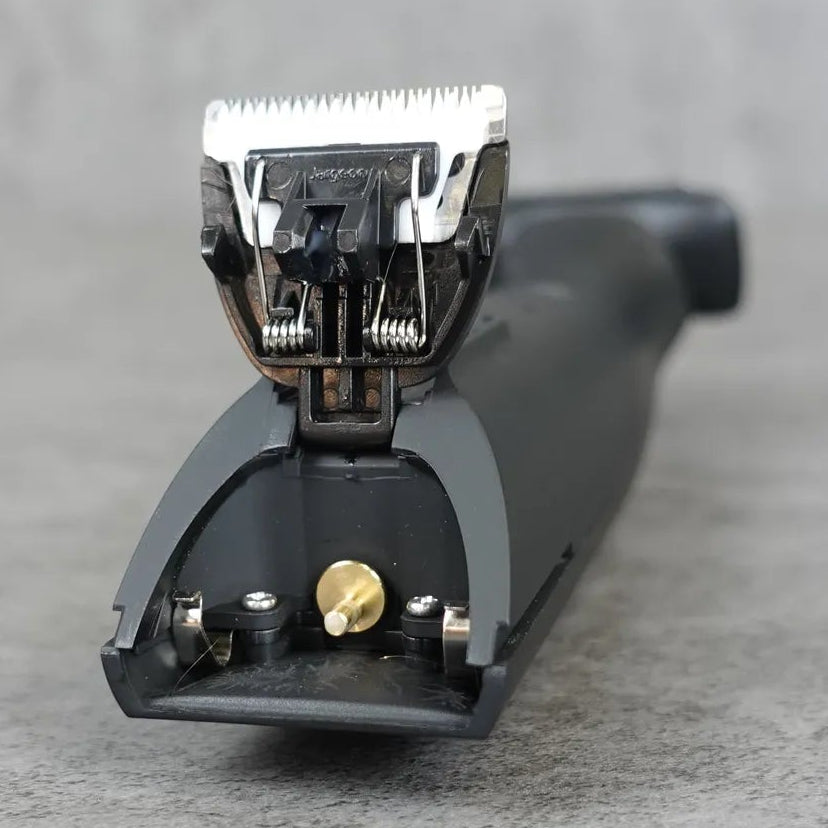 Body groomer trimmer head on a gray surface with a blurred background
