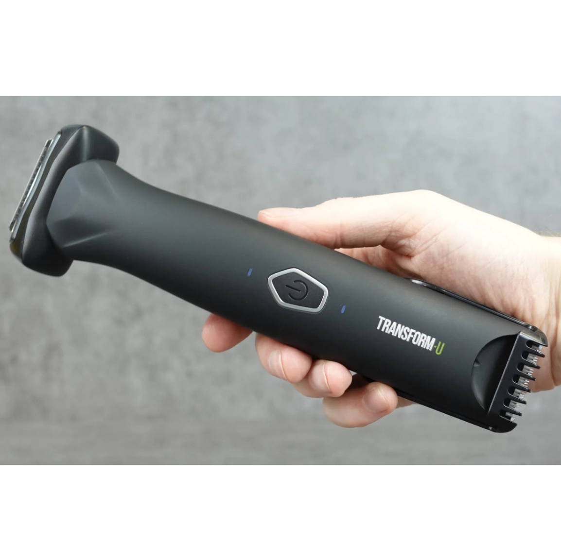 Hand holding a black body grooming tool with 'Transform-U' branding against a gray background