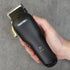 Hand holding a black hair clipper with 'TRANSFORM-U' branding on a gray background