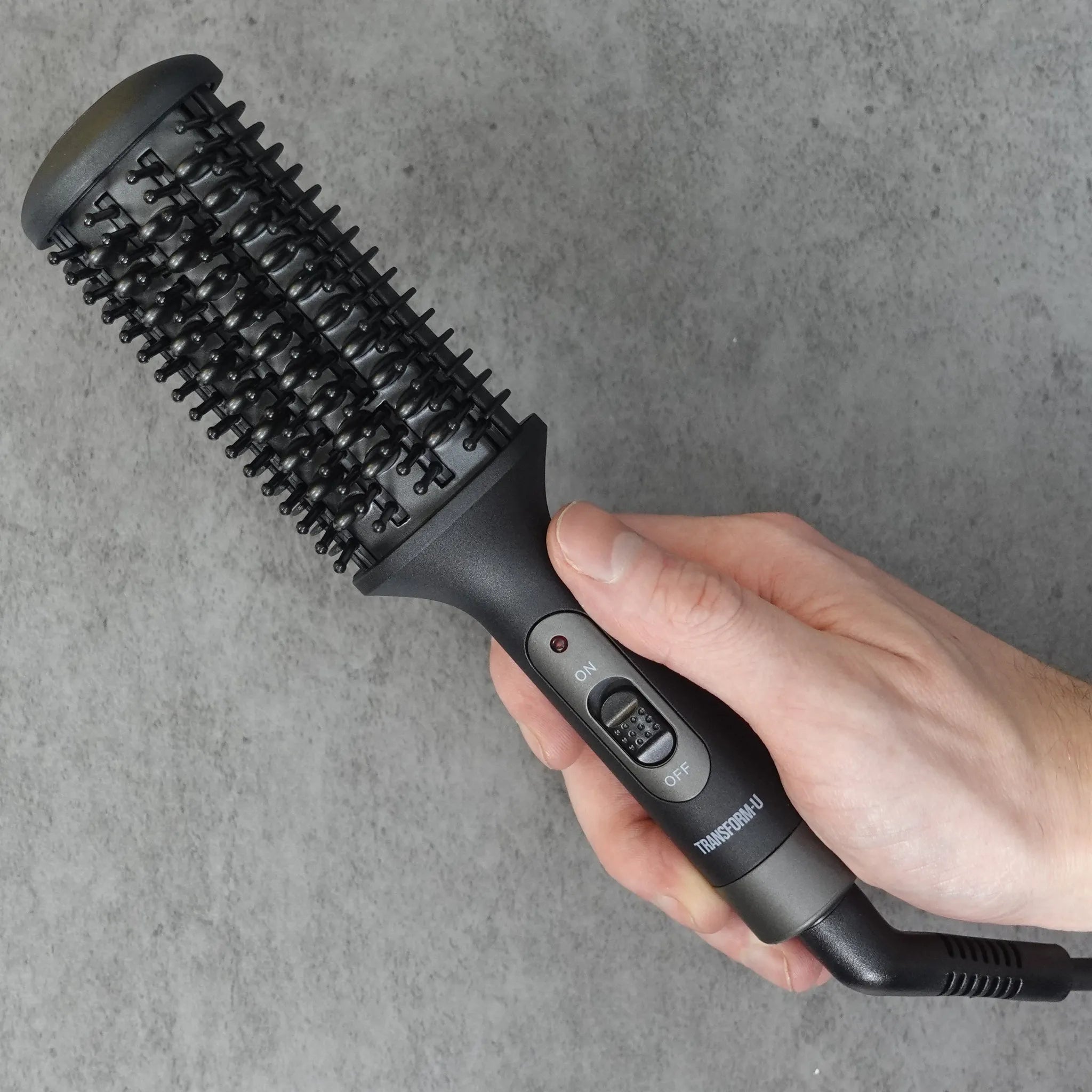 hand holding a beard straightener tool on a dark background