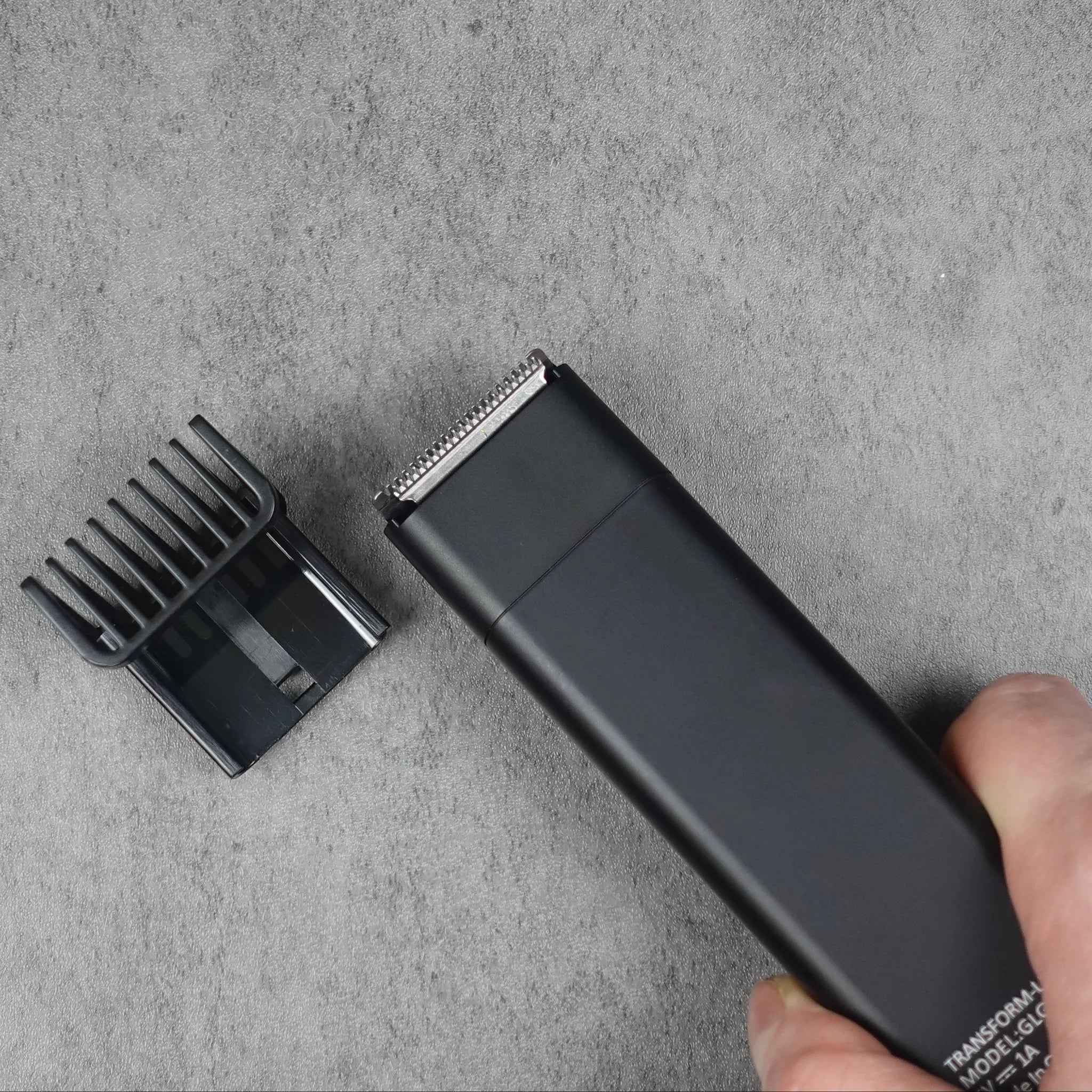 Hair trimmer with comb on a gray surface