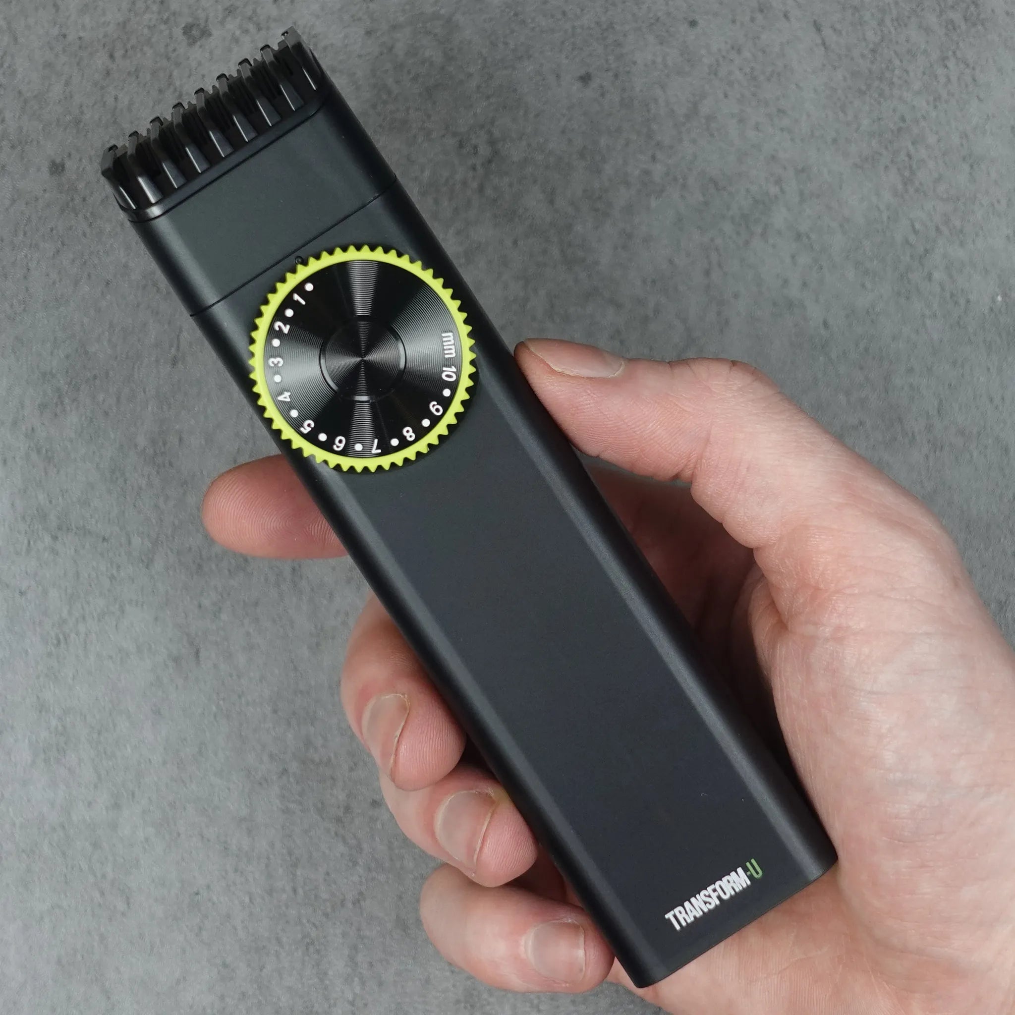 Hand holding a black hair trimmer against a gray background