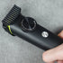 Hand holding a black hair trimmer on a gray surface