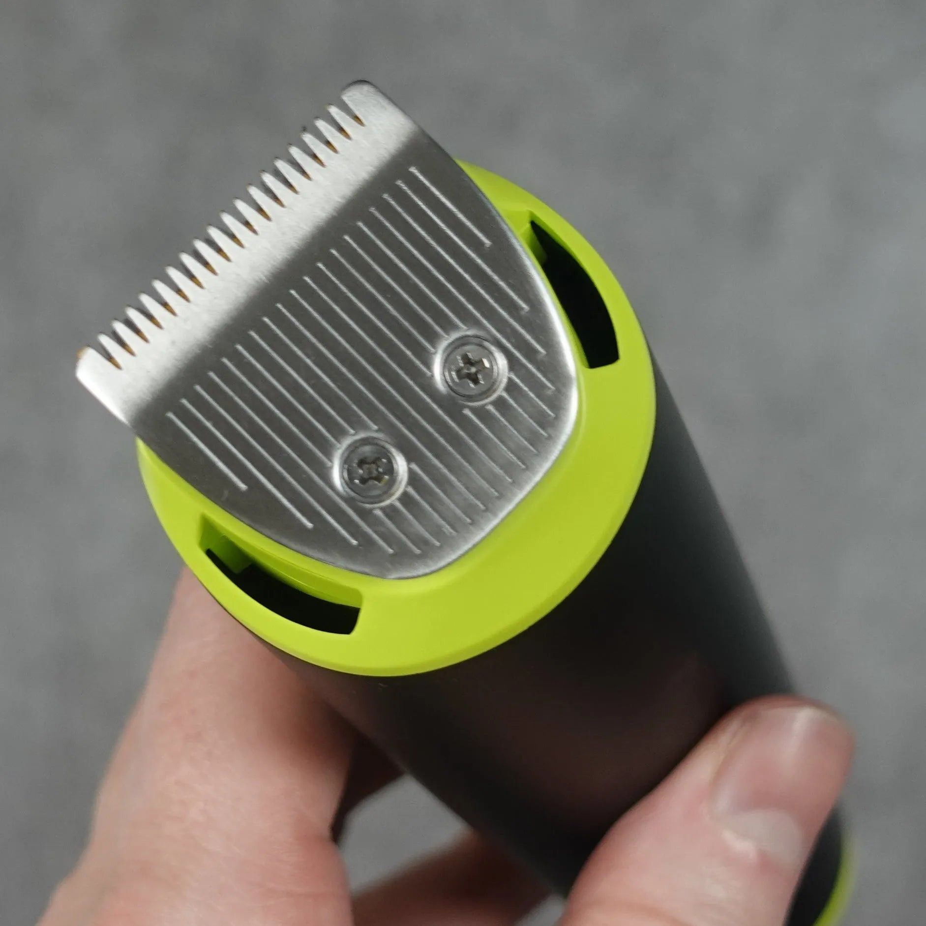 Hair trimmer held by a hand against a gray background
