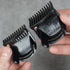 Two black hair trimmer guide combs held by hands against a gray background