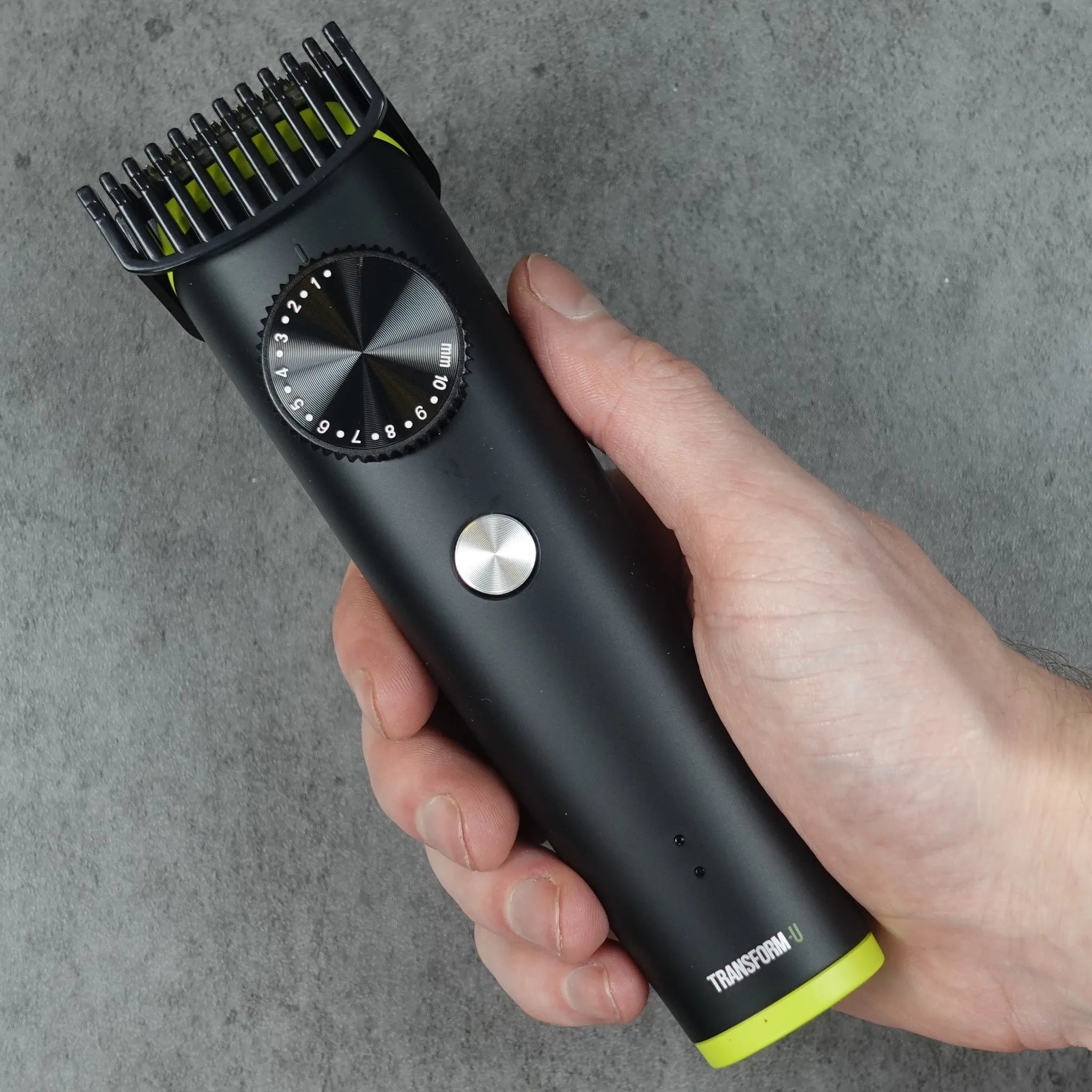 Hand holding a black hair trimmer against a gray background