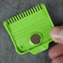 Green magnetic guide comb with measurement markings held by a hand on a gray background