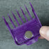 Purple hair comb attachment held by a hand against a gray background