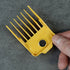 Orange magnetic guide comb held by a hand on a gray concrete surface