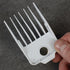 White hair clipper magnetic guide comb held by a hand on a dark background