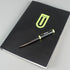 Black notebook with a logo and a pen on a gray background
