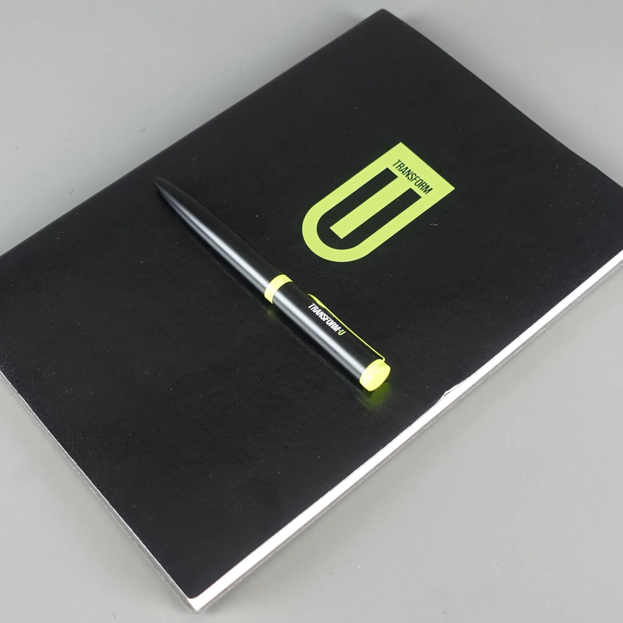 Black notebook with a pen on a gray background