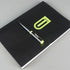 Black notebook with a pen on a gray background