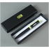Black pen with green accents in an open black box on a gray background