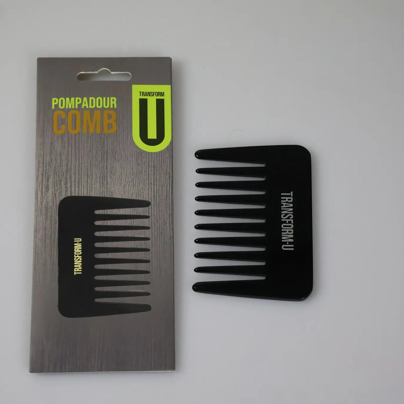 Black comb and its packaging on a gray background