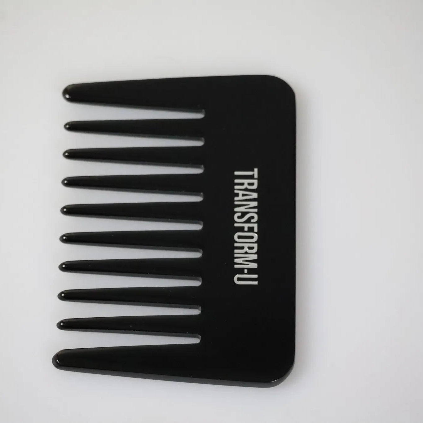 Black comb with 'Transform-U' branding on a white background