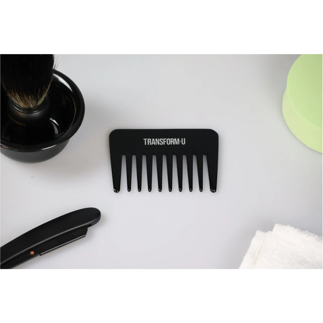 Black comb with 'TRANSFORM-U' branding on a white surface with grooming items.