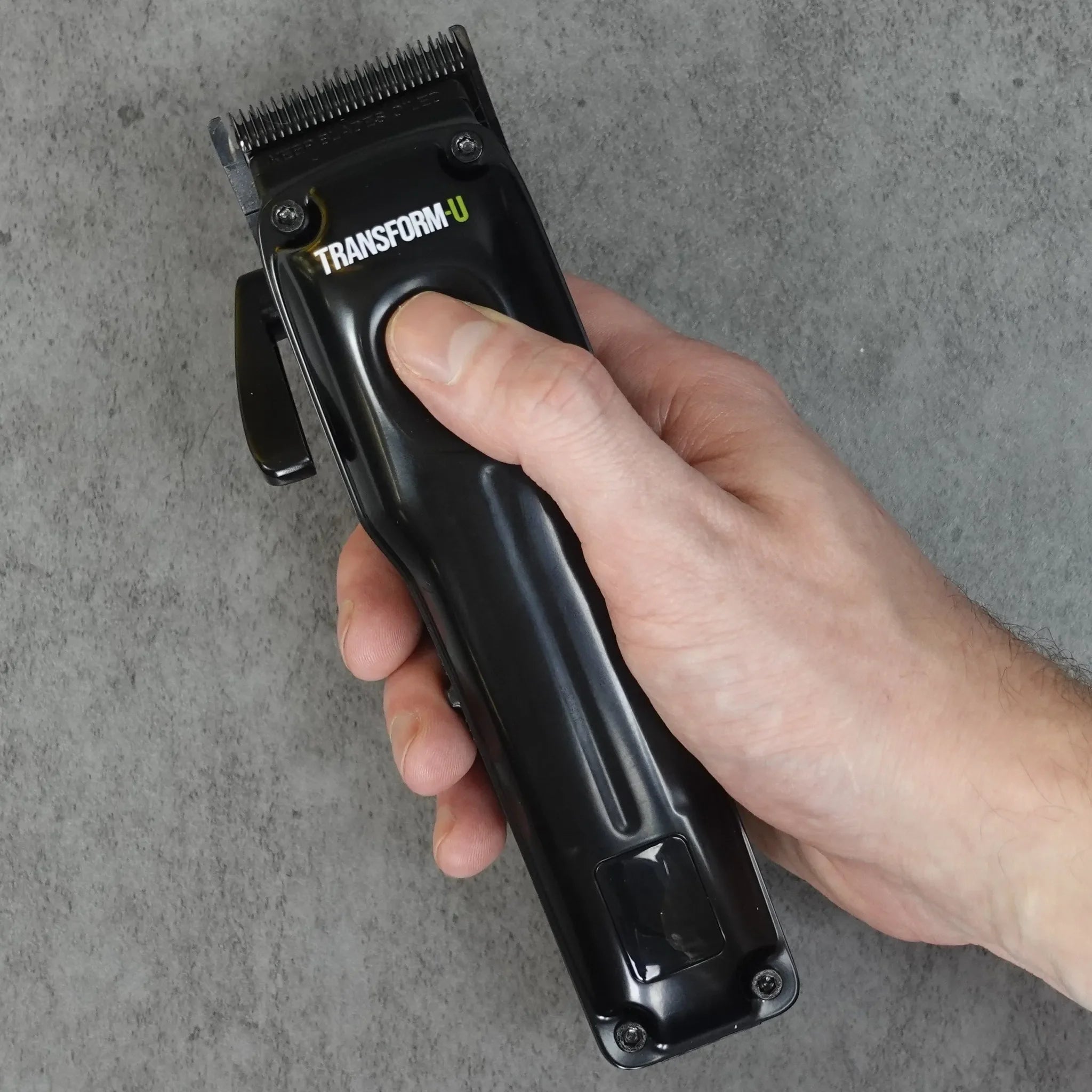 hand holding a black hair clipper on a gray background