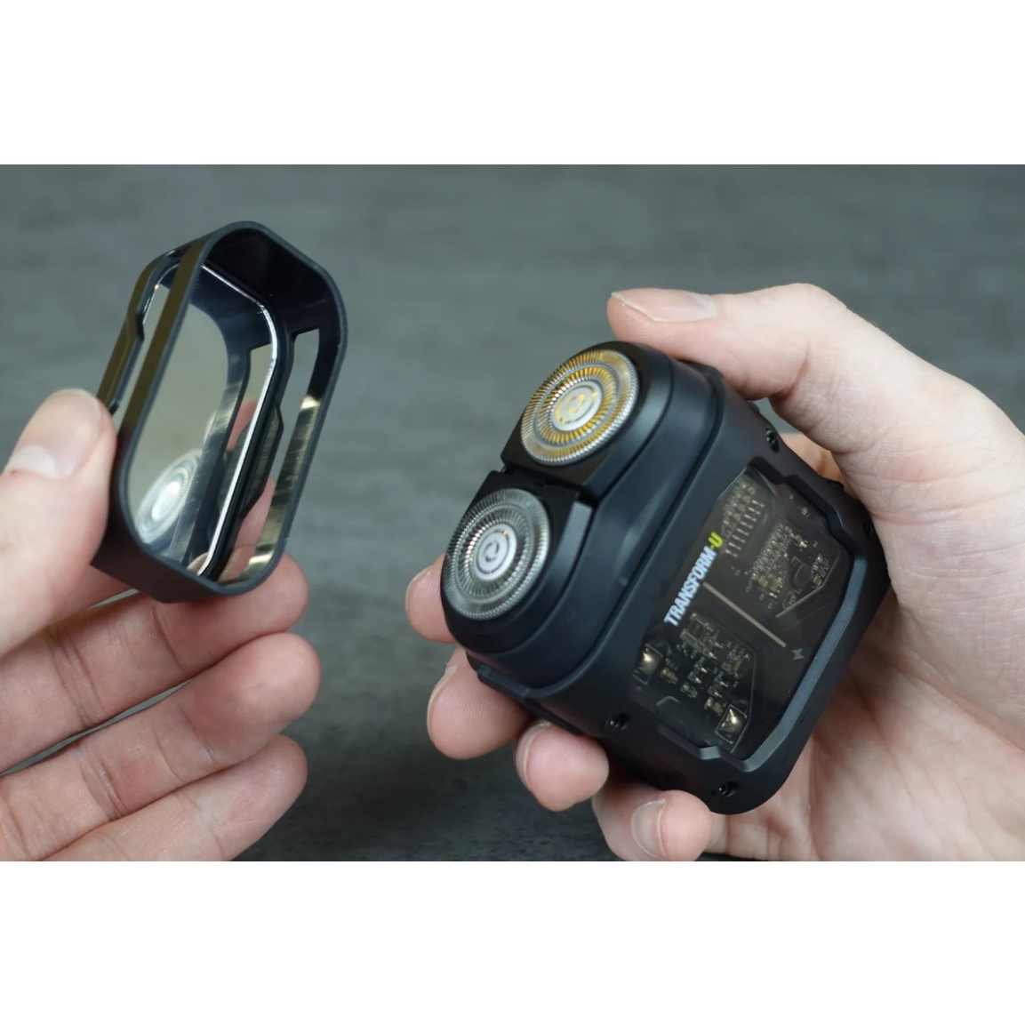 Two hands holding a travel shaver and its charging case against a gray background